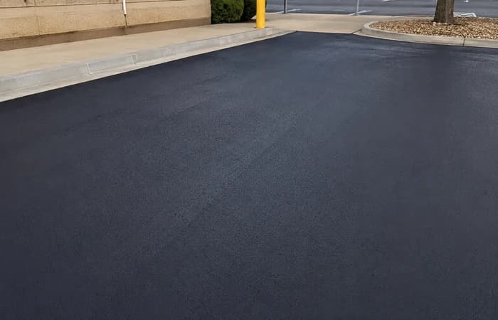 Dark sealcoated asphalt surface near a commercial curb