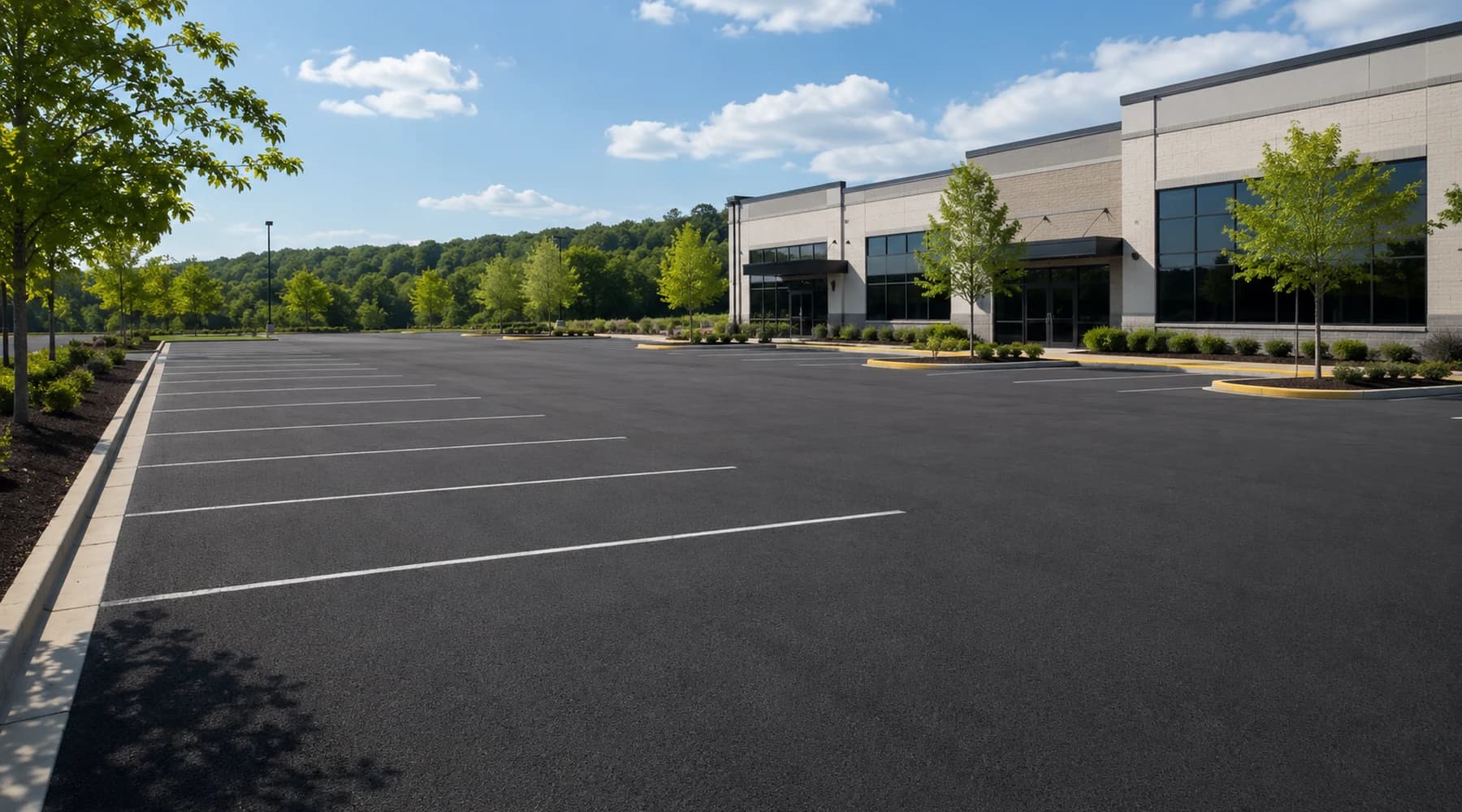 Wide commercial parking lot with dark asphalt, clean striping, and a modern building
