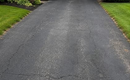 Customer-style photo of a worn residential asphalt driveway