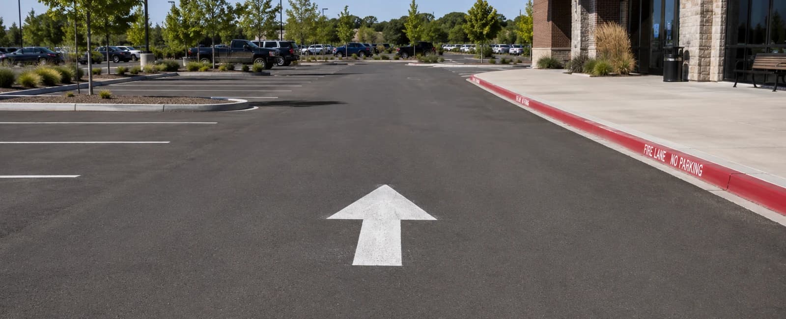 Commercial lot drive aisle with white arrows and a red fire lane curb