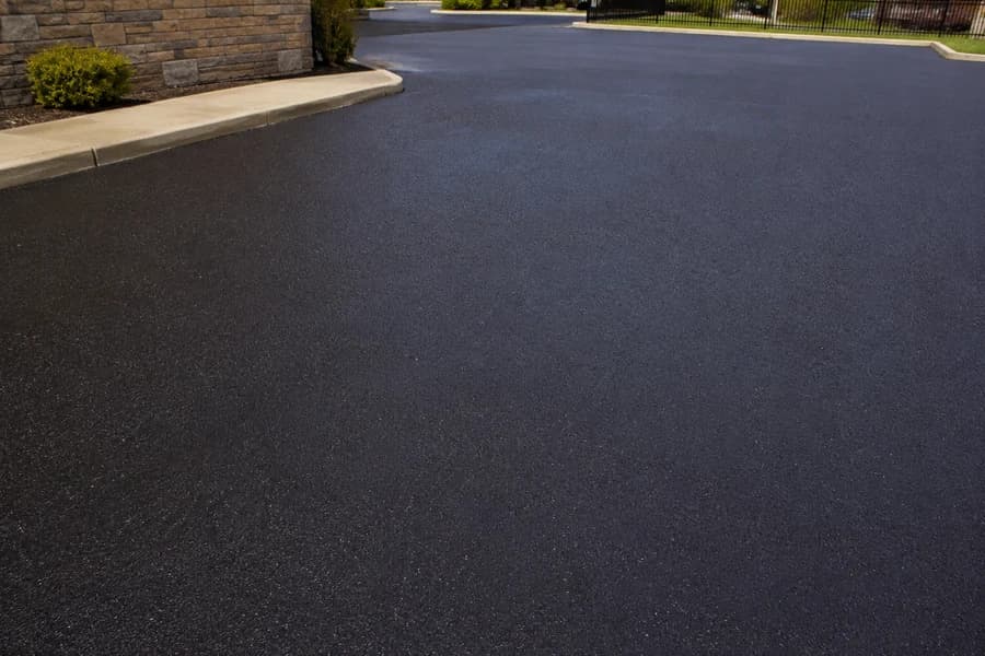 Fresh dark sealcoated asphalt surface near a commercial curb